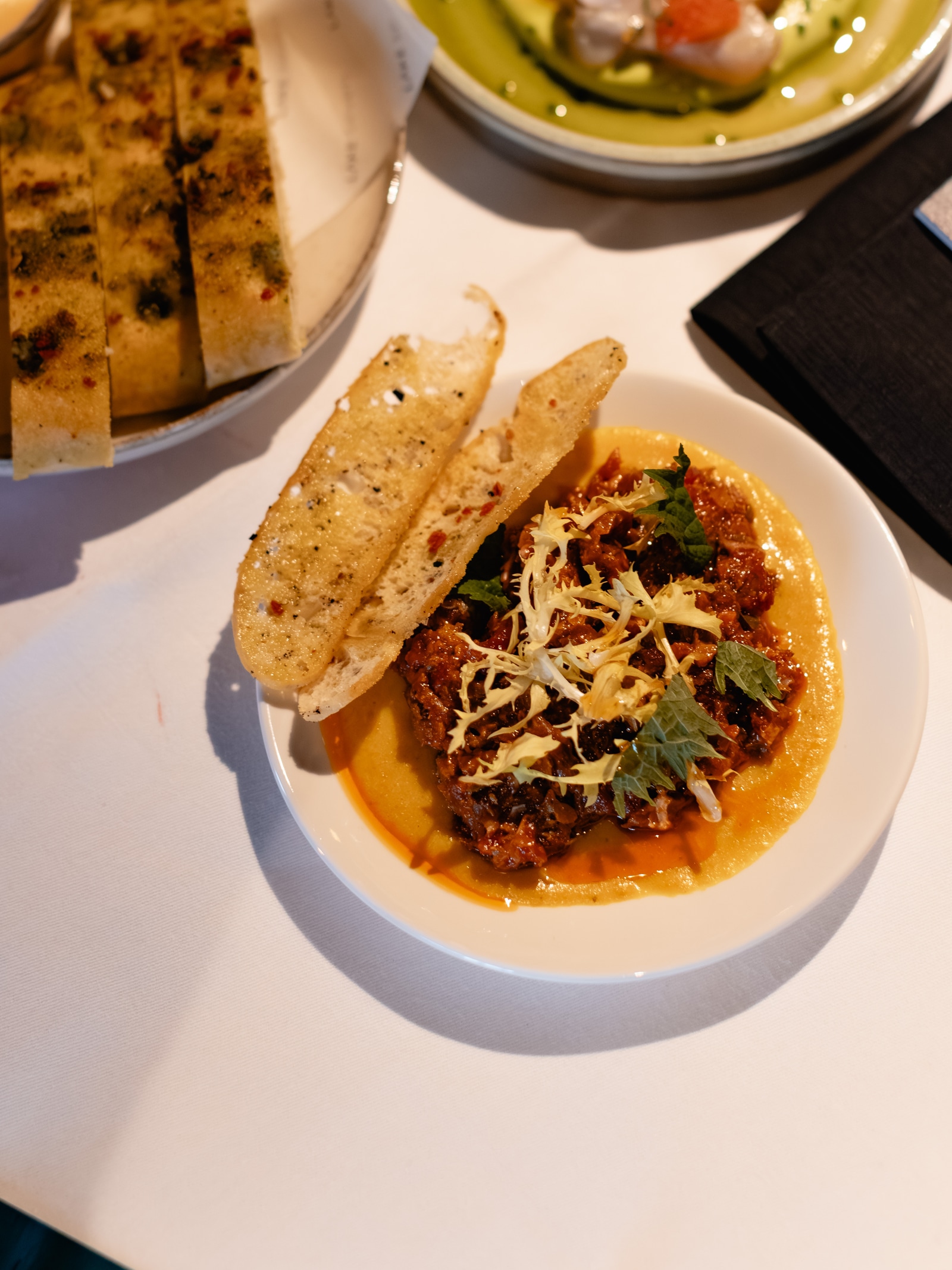 Ragù met focaccia en gegrilde crostini op tafel, met ceviche ernaast
